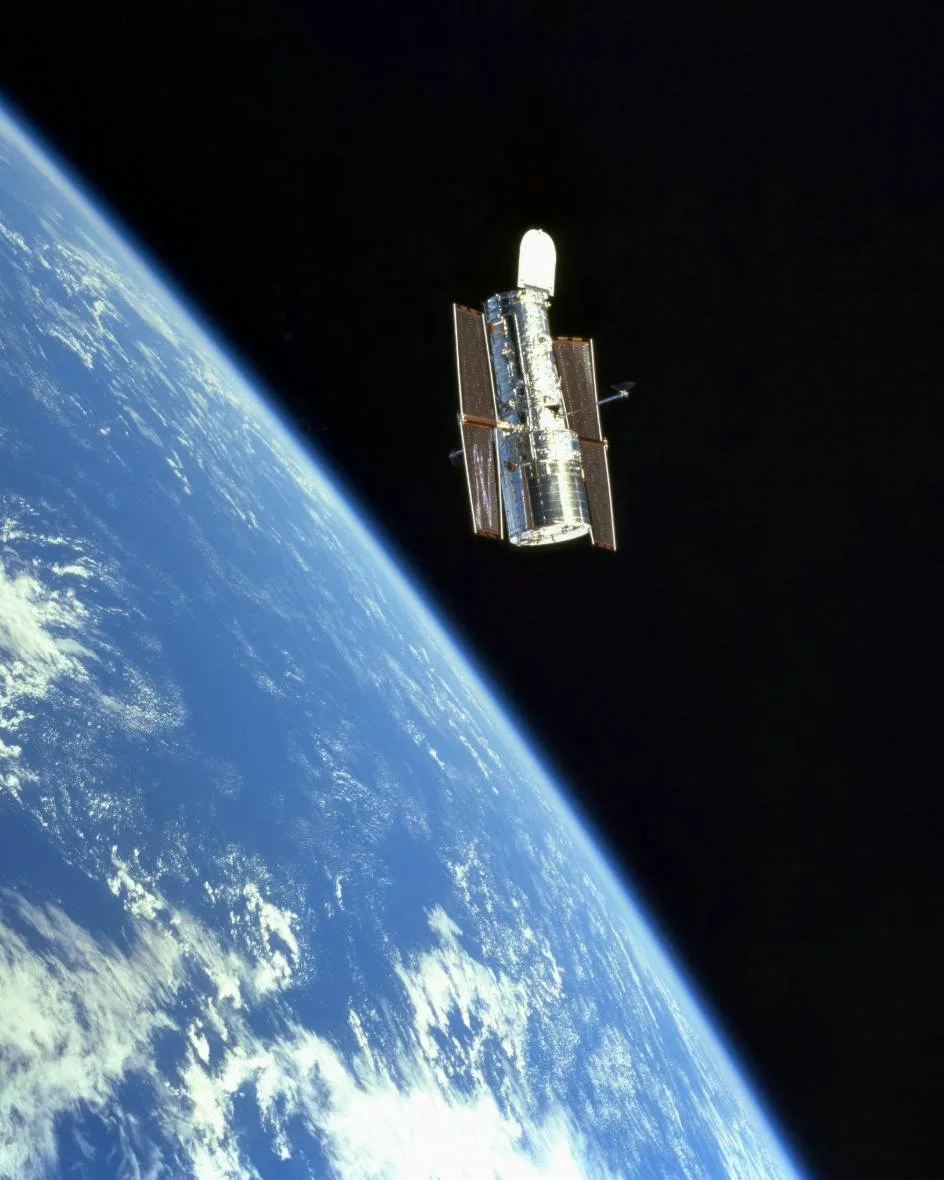 Space telescope satellite in low Earth orbit above the curve of the planet, aerospace and defense technology.