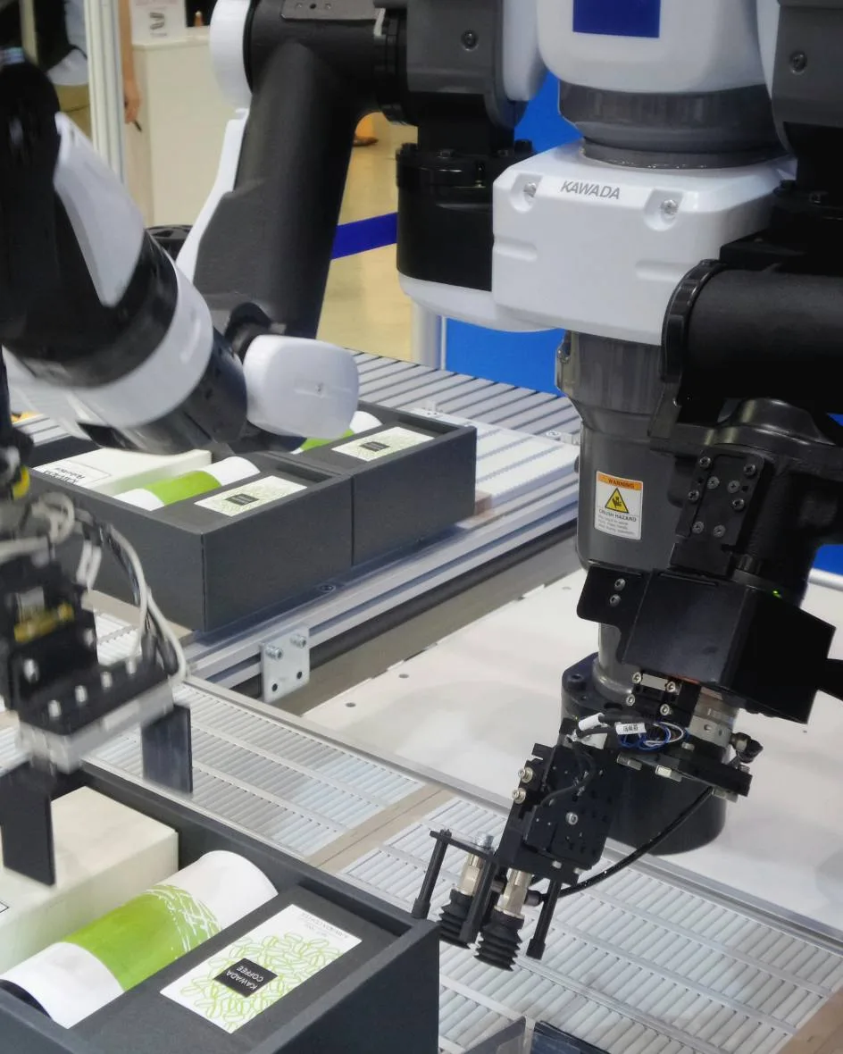 Dual-arm industrial robot assembling packaged goods in an automated production cell, robotics in manufacturing.